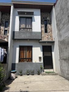 a white house with a black door and windows at Sofias Townhouse for Rent in Dasmariñas