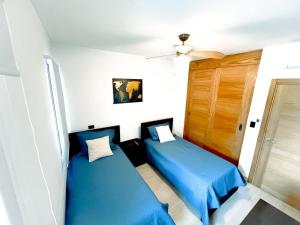 two beds in a small room with blue sheets at Estrella Garden Condos con Vista a la piscina in San Rafael del Yuma +16 photos