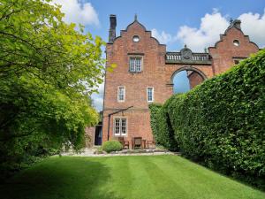 an old brick building with an arch in a yard at South Tower Cottage in Macclesfield