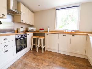 a kitchen with white cabinets and a window at South Tower Cottage in Macclesfield