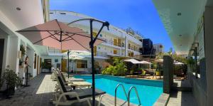 a pool with chairs and an umbrella next to a building at Hotel Miramar in Huarmey