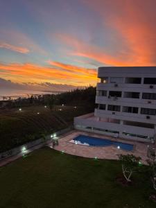 a building with a pool in front of a sunset at Vista mar nascente in São Luís