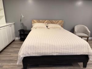 a bedroom with a bed with a white comforter and a chair at Sunset Suite in Bridgewater
