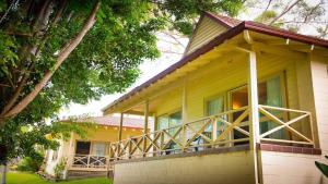 a yellow house with a large balcony on it at Pacific Palms Resort in Charlotte Bay