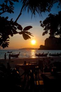 a sunset on the beach with a table and chairs at Railay Village Resort in Railay Beach