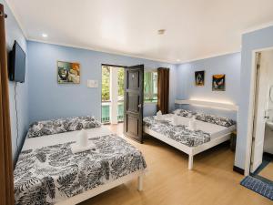 two beds in a room with blue walls at Joaquinn's Bed and Breakfast El Nido City near Beach in El Nido