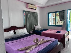 a bedroom with two beds with purple sheets and a pair of snakes at Benny sweet family in Ao Phutsa