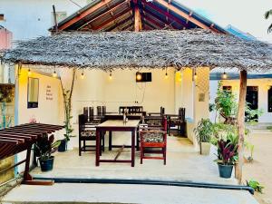 a patio with a table and chairs and a roof at Lagoon Hostel in Arugam Bay