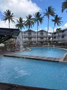 a large swimming pool with a fountain in front of palm trees at Appartement ALYA in Les Trois-Îlets