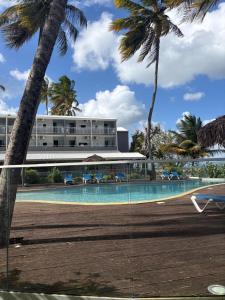 a resort with a swimming pool and palm trees at Appartement ALYA in Les Trois-Îlets