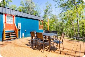 a deck with a table and chairs and a blue house at Serenity Cabin - Cozy Mountain retreat near Shenandoah National Park in Luray