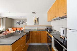 a kitchen with wooden cabinets and a couch at Stylish 2-Bed Stay with Pool & Parking in Canberra