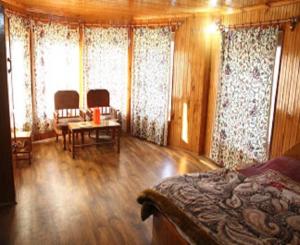 a bedroom with a bed and a table and windows at Pine inn in Pahalgām