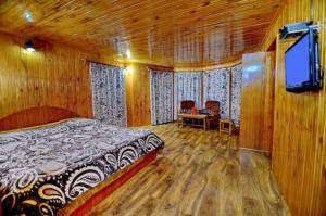 a bedroom with a bed and a tv and wooden walls at Pine inn in Pahalgām