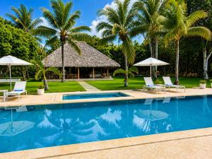 a resort swimming pool with chairs and umbrellas at Miara - Celebrity villa in Casa de Campo! in La Romana