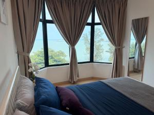 a bedroom with large windows and a bed with blue sheets at SEAVIEW - BEACHFRONT - 2BR Apartment - Corner Unit- Mutiara Melaka Beach Resort Pantai Puteri in Malacca +47 photos