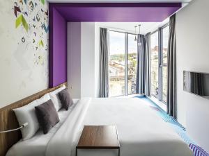 a bedroom with a large bed with purple ceilings at Ibis Styles Lviv Center in Lviv +158 photos