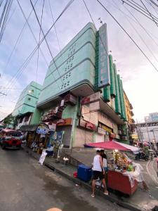 two people walking down a street in front of a building at Nice Hotel Arayat Cubao in Manila +4 photos