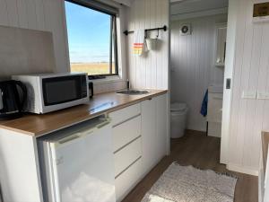 a kitchen with a microwave on a counter with a window at Loft Tiny House by Tiny Away in Banyena