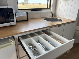 a kitchen with a sink and a microwave and a drawer at Loft Tiny House by Tiny Away in Banyena