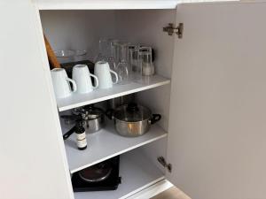 a kitchen pantry with white shelves and appliances at Loft Tiny House by Tiny Away in Banyena +17 photos
