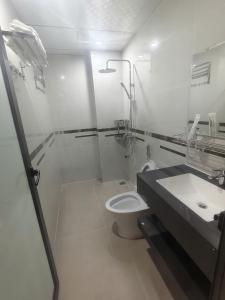 a white bathroom with a toilet and a sink at Hotel Xanh Fly in Nhật Tựu