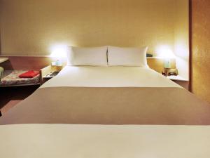a large bed in a hotel room with two lamps at ibis Arapiraca in Arapiraca