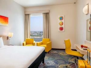 a hotel room with a bed and a desk and chairs at Ibis Styles Dragon Mart Dubai in Dubai