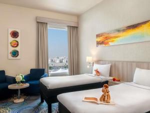 a hotel room with two beds and a window at Ibis Styles Dragon Mart Dubai in Dubai +101 photos