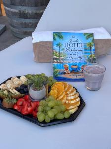 a tray of fruit on a table with a book at Beach Hotel Božikovina 2 in Podstrana