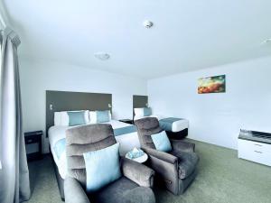 a bedroom with a bed and a pair of chairs at BKs Premier Motel Hamilton in Hamilton