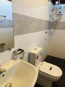a bathroom with a white toilet and a sink at Chaya Villa Sigiriya in Sigiriya +88 photos