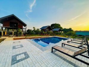 a swimming pool with two benches and a house at Chaya Villa Sigiriya in Sigiriya