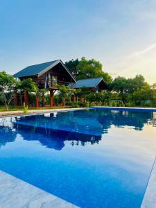 a large pool of blue water in front of a house at Chaya Villa Sigiriya in Sigiriya