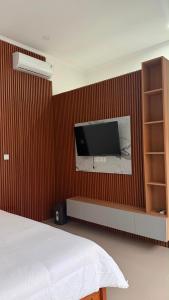 a bedroom with a tv on a red wall at Rdm Bali Guest House in Badung