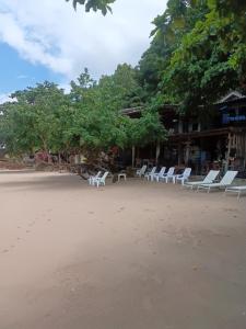 a group of white lounge chairs on a beach at Changbar Bungalow in Ban Ao Sapparot