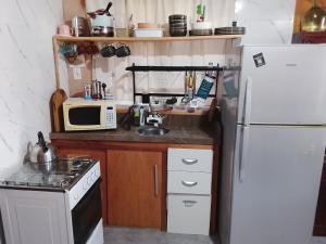 a small kitchen with a white refrigerator and a microwave at Gather in Balneario Argentino +10 photos