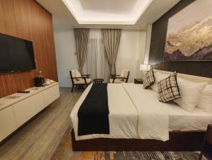 ein Hotelzimmer mit einem großen Bett und einem Fernseher in der Unterkunft Madayaw Hotel Tagum in Tagum