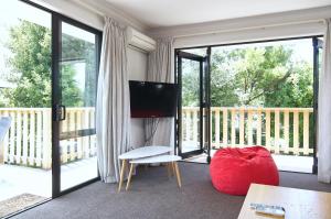 a living room with a television and sliding glass doors at Brookside Villa - Christchurch Holiday Homes in Christchurch