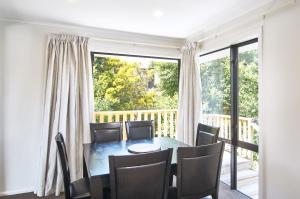 a dining room with a table and chairs and a large window at Brookside Villa - Christchurch Holiday Homes in Christchurch