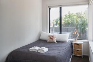 a bedroom with a bed and a large window at Brookside Villa - Christchurch Holiday Homes in Christchurch