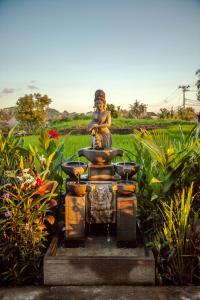 a statue sitting on top of a fountain in a garden at Kama Bisma Cottage in Ubud