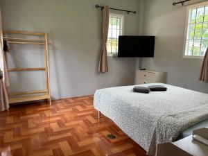 a bedroom with a bed and a flat screen tv at Mango Guest House Choeng Thale in Ban Thalat Choeng Thale