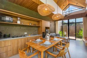 a kitchen and dining room with a wooden table and chairs at Ellavie Villa Ubud in Ubud