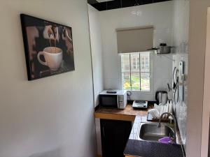 a small kitchen with a sink and a microwave at Mango Guest House Choeng Thale in Ban Thalat Choeng Thale