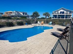 a swimming pool in front of a house at Somewhere South home in Holden Beach