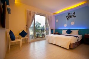 a bedroom with a large bed and a balcony at Millennium Inn II in Kenting