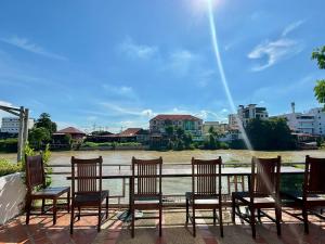 a group of chairs sitting in front of a river at Ayothaya Riverside Hotel in Phra Nakhon Si Ayutthaya