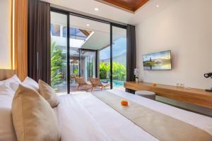 a bedroom with a large bed and glass walls at Ellavie Villa Ubud in Ubud +32 photos