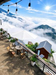 a table and chairs on a balcony with a view of mountains at Xìu Homestay Tà Xùa in Bắc Yên